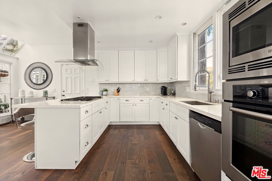 12320 Ridge Circle Los Angeles, CA 90049 - Photo 4 of 38 a white kitchen with stainless steel appliances granite countertop a stove a sink and a microwave