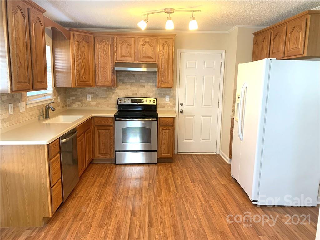210 Forest Pond Road Kannapolis, NC 28083 - Photo 2 of 10 a kitchen with a sink a refrigerator a stove and wooden cabinets