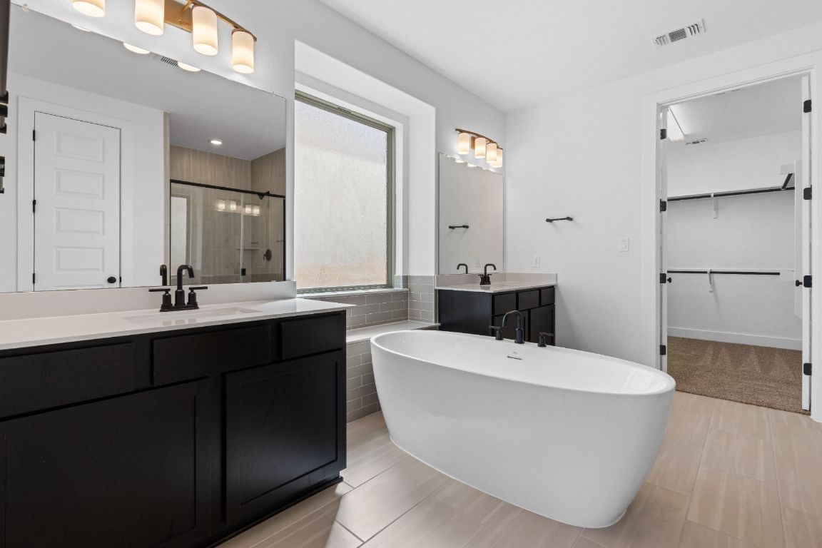 1620 Lilly Grace Bend Leander, TX 78641 - Photo 17 of 40 a bathroom with a bathtub sink a mirror and a shower