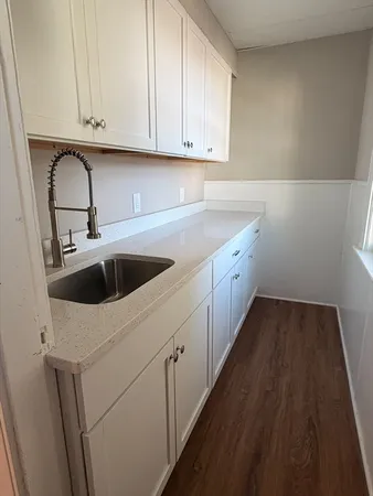 a kitchen with granite countertop white cabinets and sink