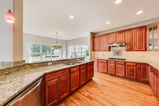 a large kitchen with granite countertop wooden cabinets a sink and dishwasher