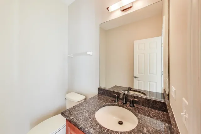 a bathroom with a granite countertop sink toilet and mirror