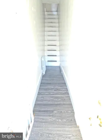 a view of a hallway with wooden floor and a bathroom