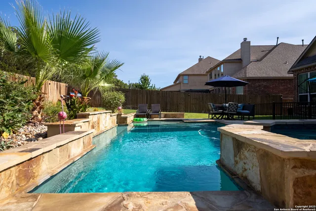 a view of a backyard with swimming pool and furniture
