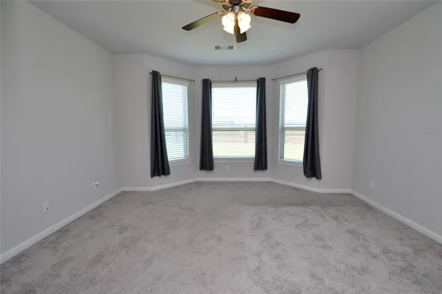 an empty room with windows and chandelier fan