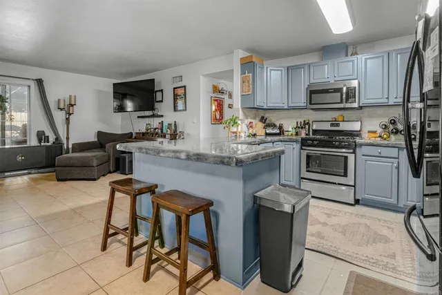 a kitchen with stainless steel appliances granite countertop a stove top oven a sink dishwasher a dining table and chairs with wooden floor