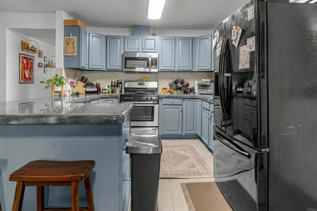 a kitchen with kitchen island granite countertop a stove top oven a sink dishwasher and cabinets