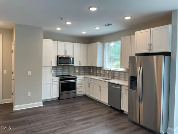 a kitchen with stainless steel appliances granite countertop a refrigerator and a stove top oven