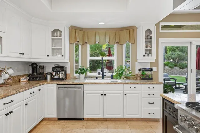 a kitchen with granite countertop white cabinets and utility room