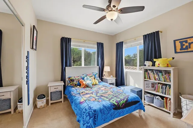 a bedroom with a bed a desk and chair with window