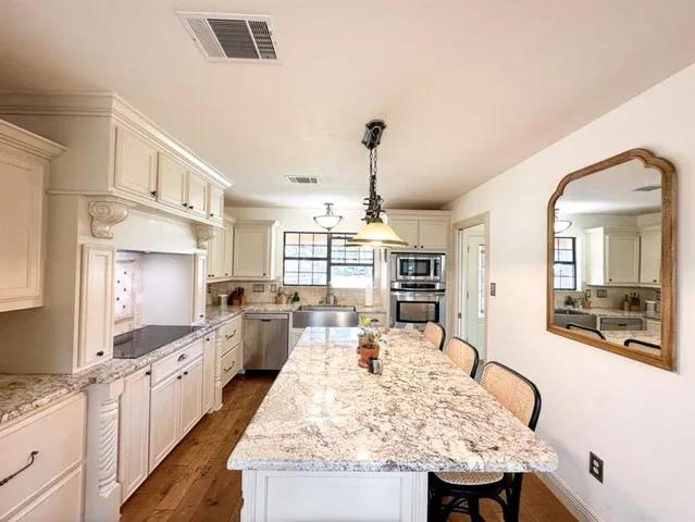 a kitchen with kitchen island white cabinets and stainless steel appliances
