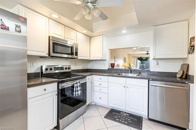 a kitchen with granite countertop a sink stainless steel appliances and white cabinets