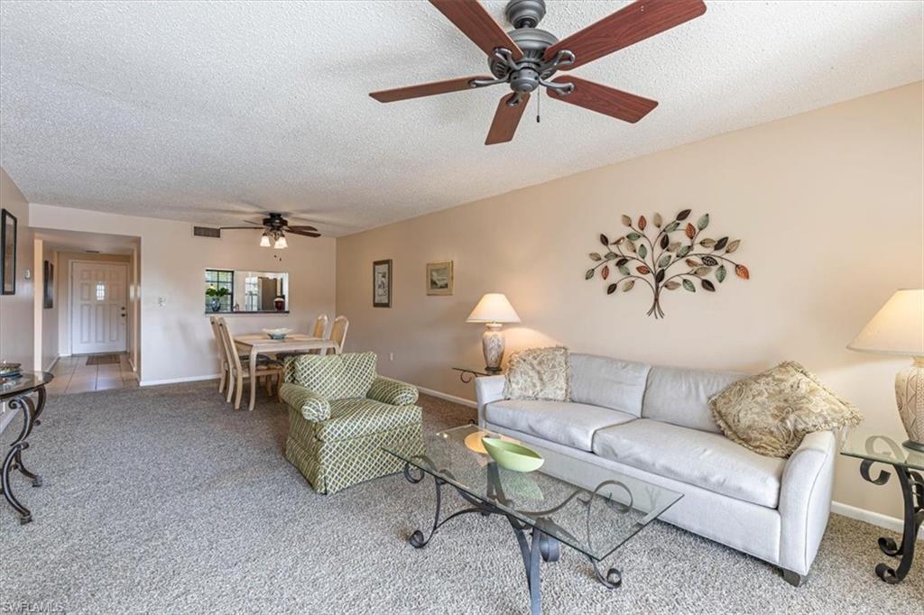 5535 Rattlesnake Hammock Road, Unit 302 Naples, FL 34113 - Photo 5 of 24 a living room with furniture and a chandelier