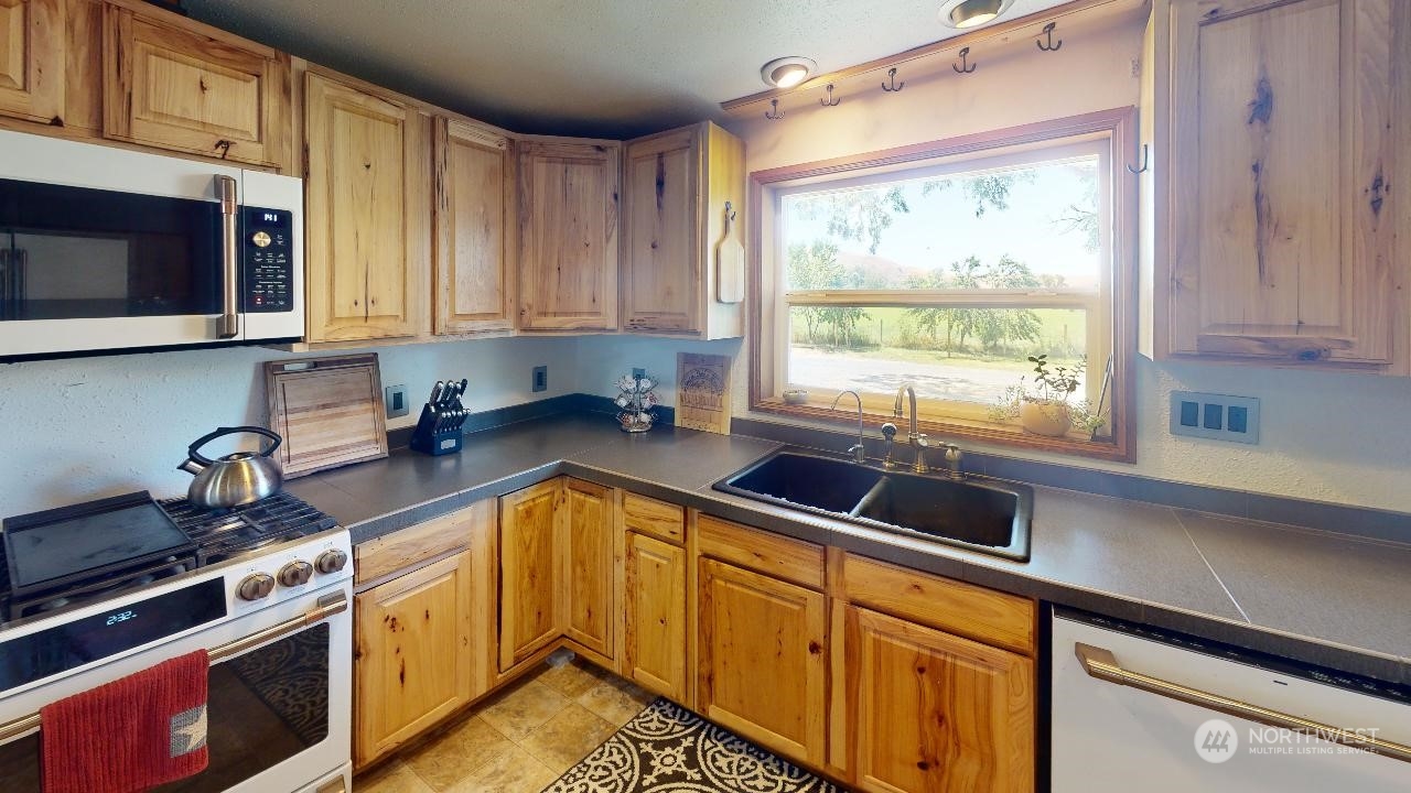 216 Tucannon Road Dayton, WA 99328 - Photo 6 of 39 a kitchen with granite countertop a sink stainless steel appliances a counter space and cabinets