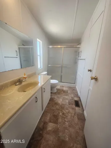 a spacious bathroom with a granite countertop sink a toilet a mirror and shower