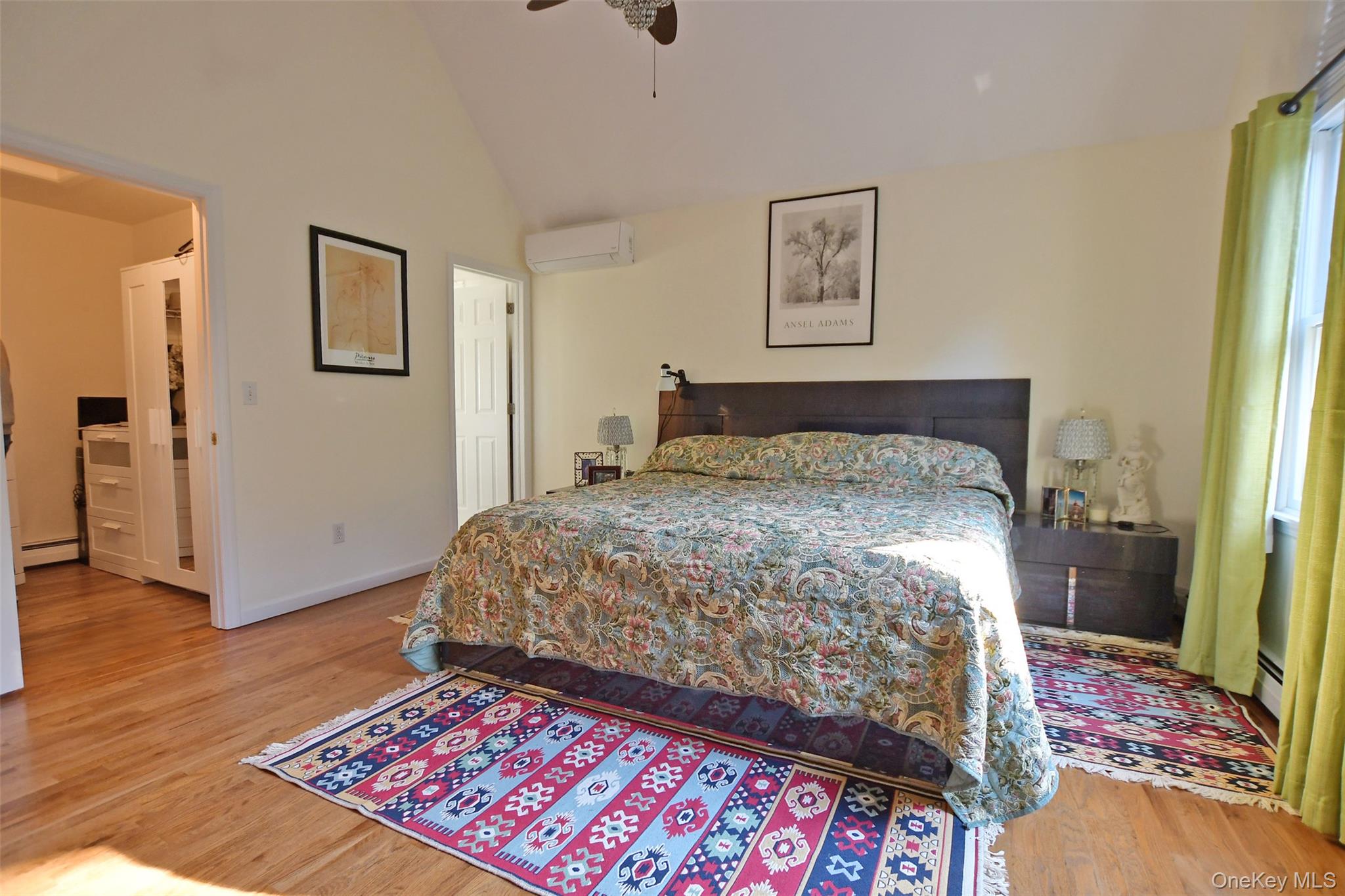 64 Glen Road Baiting Hollow, NY 11933 - Photo 16 of 46 Bedroom with light wood-type flooring, a ceiling fan, a wall mounted air conditioner, a baseboard radiator, and high vaulted ceiling