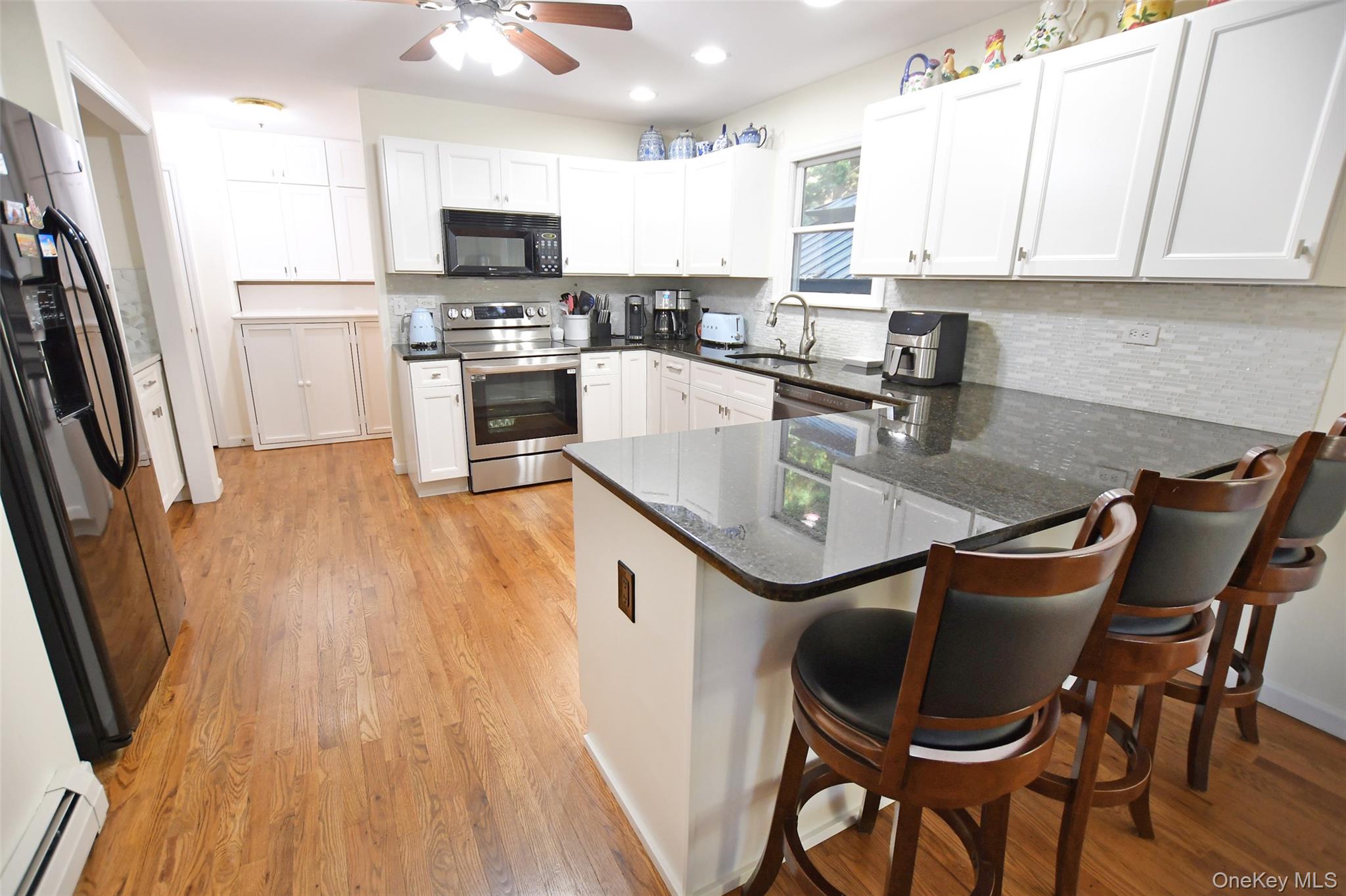 64 Glen Road Baiting Hollow, NY 11933 - Photo 9 of 46 Kitchen with dark stone countertops, white cabinetry, black appliances, a kitchen breakfast bar, and recessed lighting