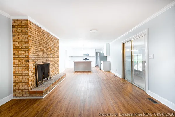 a view of a livingroom with wooden floor and a fireplace