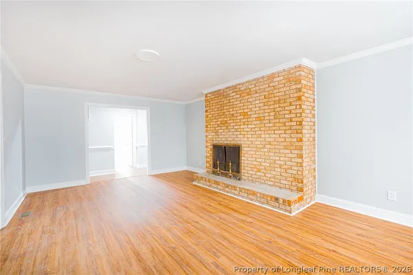 a view of empty room with wooden floor and fireplace