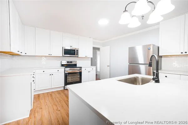 a kitchen with granite countertop a sink stainless steel appliances and white cabinets