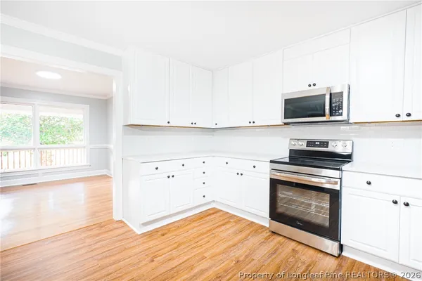 a kitchen with granite countertop a stove a microwave and view living room