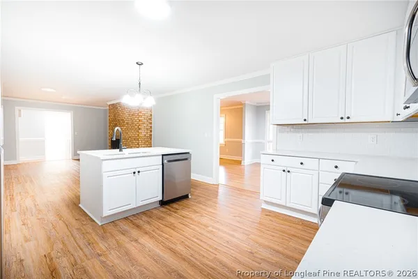 a kitchen with wooden floors white cabinets and stainless steel appliances