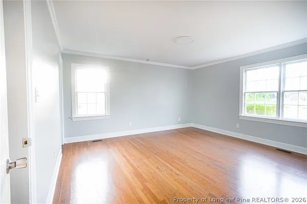 an empty room with wooden floor and windows