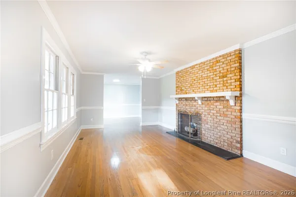 a view of empty room with wooden floor and fan