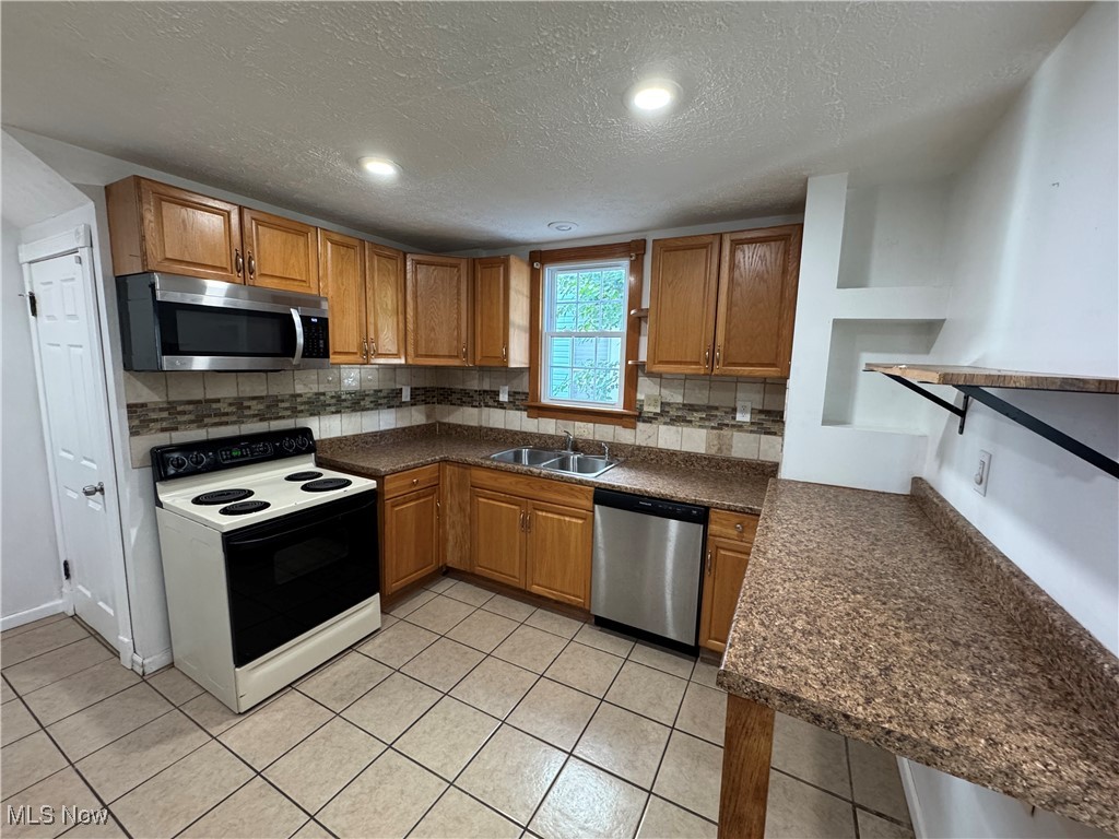 2425 7th Street Northwest Canton, OH 44708 - Photo 8 of 19 Kitchen with stainless steel appliances, decorative backsplash, brown cabinetry, a textured ceiling, and recessed lighting