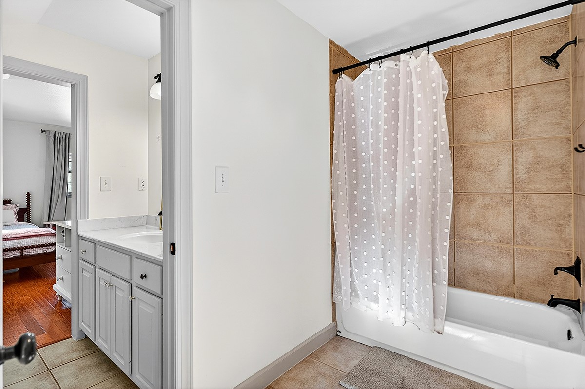 301 Medlin Creek Loop Dripping Springs, TX 78620 - Photo 23 of 40 Upstairs jack and jill bathroom with curtain, connected bathroom, and light tile patterned floors