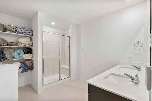 a spacious bedroom with a bed a dresser and a chandelier