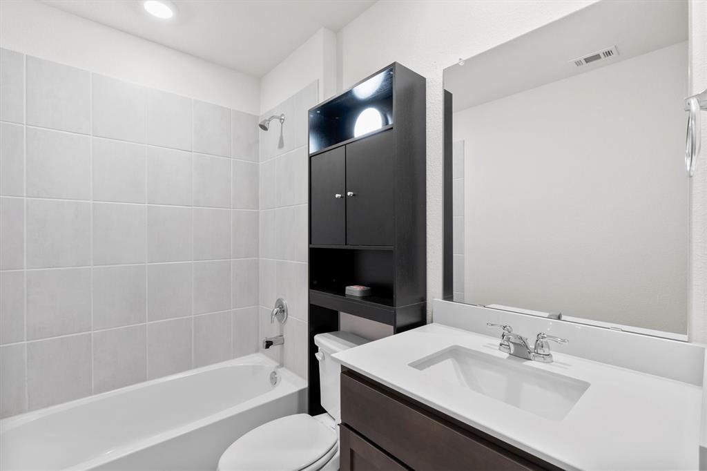 1302 Colonial Bluff Lane Princeton, TX 75407 - Photo 17 of 35 a bathroom with a bathtub shower sink vanity and toilet