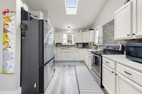 a kitchen with granite countertop a refrigerator a sink and white cabinets