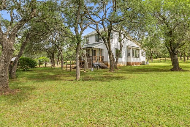 a view of a big house with a big yard and large trees