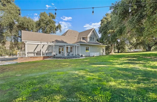 a view of a white house with a yard and large tree