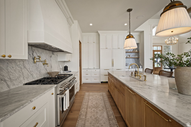478 South Maple Lakes Drive Mapleton, UT 84664 - Photo 5 of 51 Gourmet kitchen featuring a large central island with seating, a range with a pot filler, extensive white cabinetry, brass hardware, and stone countertops