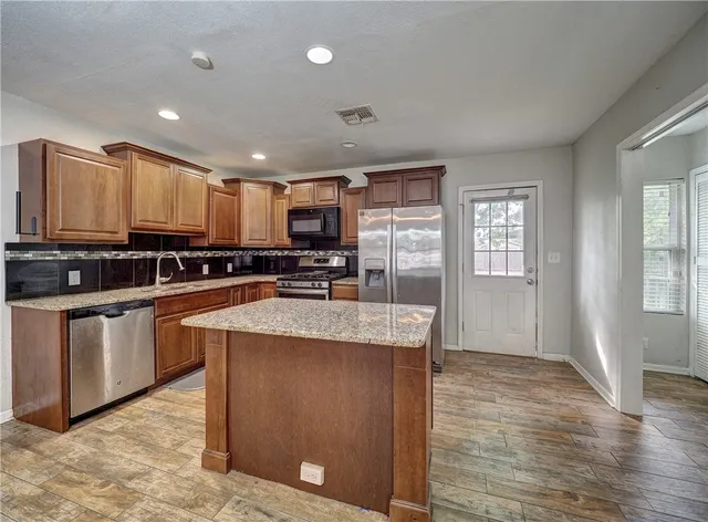a kitchen with stainless steel appliances granite countertop a sink stove refrigerator and cabinets