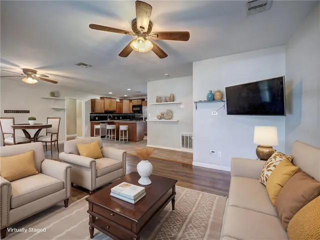 a view of a livingroom with a flat screen tv wooden floor and a ceiling fan