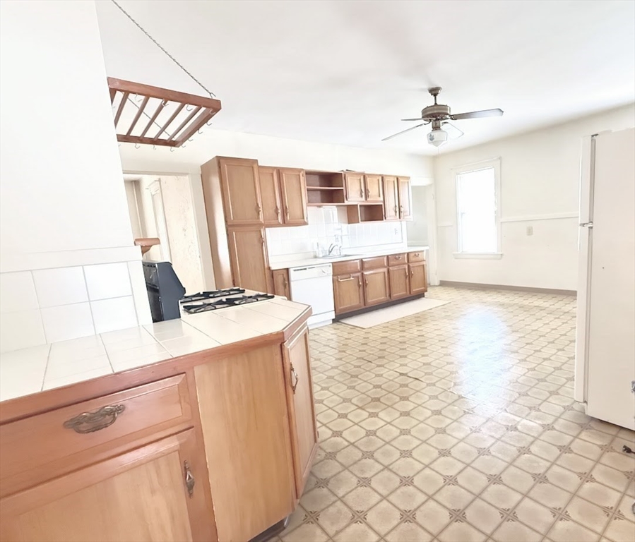 a large white kitchen with a stove a sink dishwasher and a refrigerator