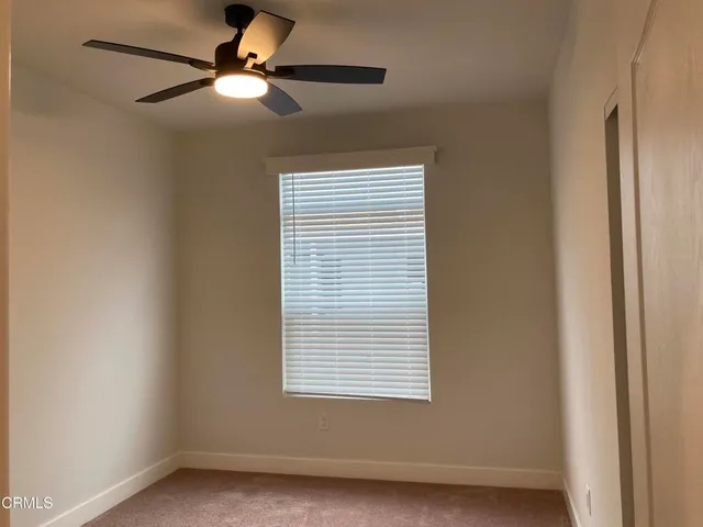 an empty room with a ceiling fan and a window