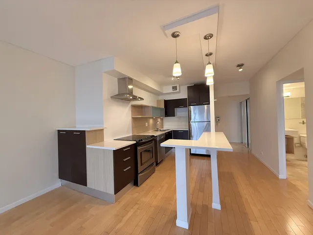 a kitchen with stainless steel appliances kitchen island a hardwood floor and a sink