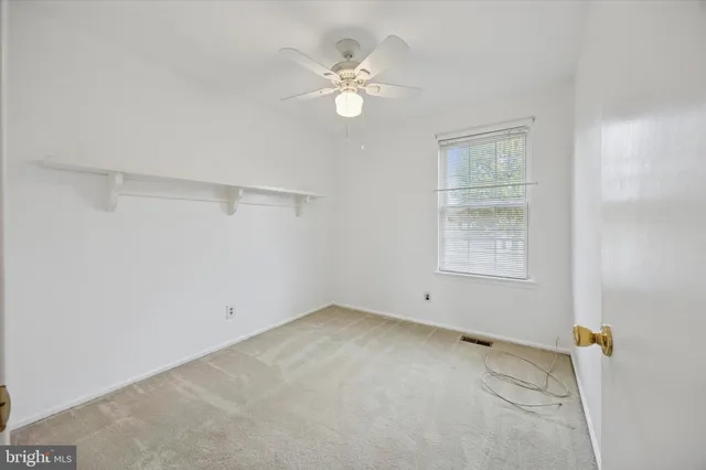 an empty room with a window and a ceiling fan
