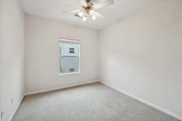 an empty room with a window and a fan