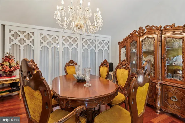 a dining room with chandelier and wooden floor