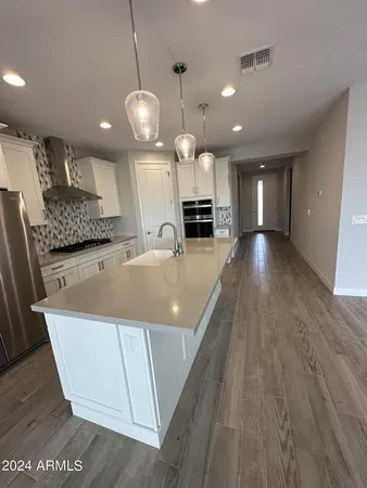a view of a room with kitchen island stainless steel appliances sink refrigerator and fireplace