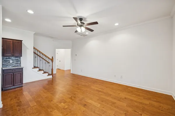 an empty room with chandelier fan and windows