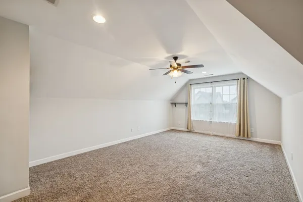 an empty room with windows and chandelier fan