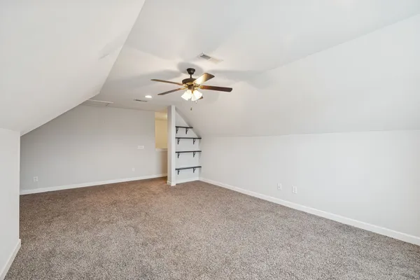 an empty room with chandelier fan and windows