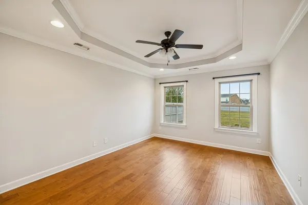 a view of empty room with wooden floor and fan