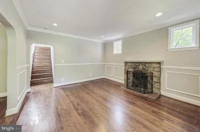 an empty room with wooden floor fireplace and windows